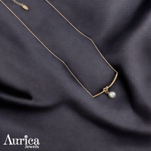 The Pearl Arc Pendant exudes timeless sophistication with its sleek metallic design and luminous pearl centrepiece.