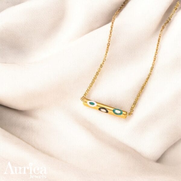 The Enchanted Charm Pendant blends modern design with artistic flair, showcasing a sleek golden metallic bar adorned with colourful enamel circles.
